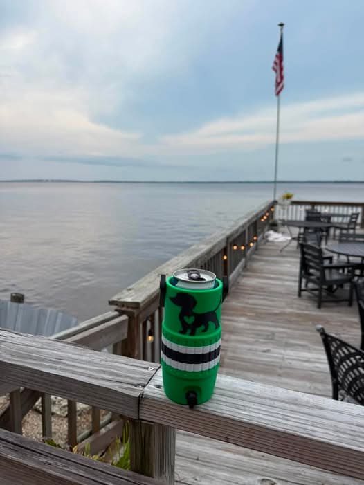 Green custom Dachshund 3D printed skinny can koozie holding a 12 oz can on a waterfront deck